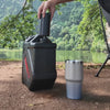 Fitting the TAHAN dispenser onto a water container at a riverside campsite